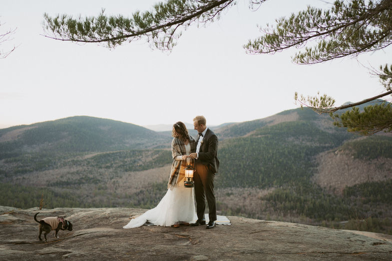 Couple exploring at sunrise with their dog for their elopement day on a mountain.