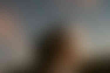 Couple exploring and enjoying sunset from a mountain top for Crawford Notch elopement day in the White Mountains for an adventure elopement. The mountains behind them are in peak foliage in nh and the sun is golden as it sets.