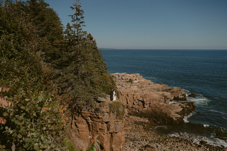 Monument cove couple exploring on cliffs on wedding day