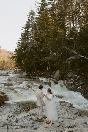 Couple sharing vows with waterfall behind them for loon mountain elopement