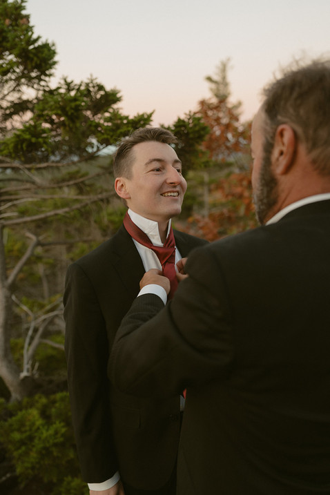 Groom getting ready with his dad on a mountain top at sunrise for elopement with family in the white mountains