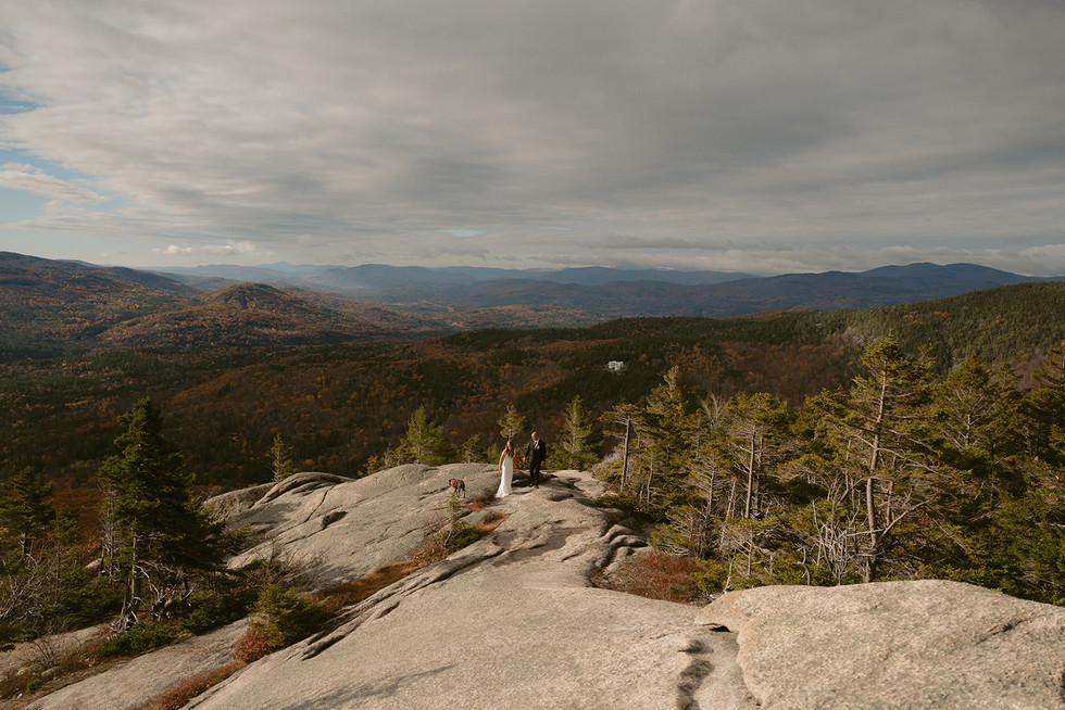 Couple on mountain top in franconia notch on elopement day enjoying sunrise.