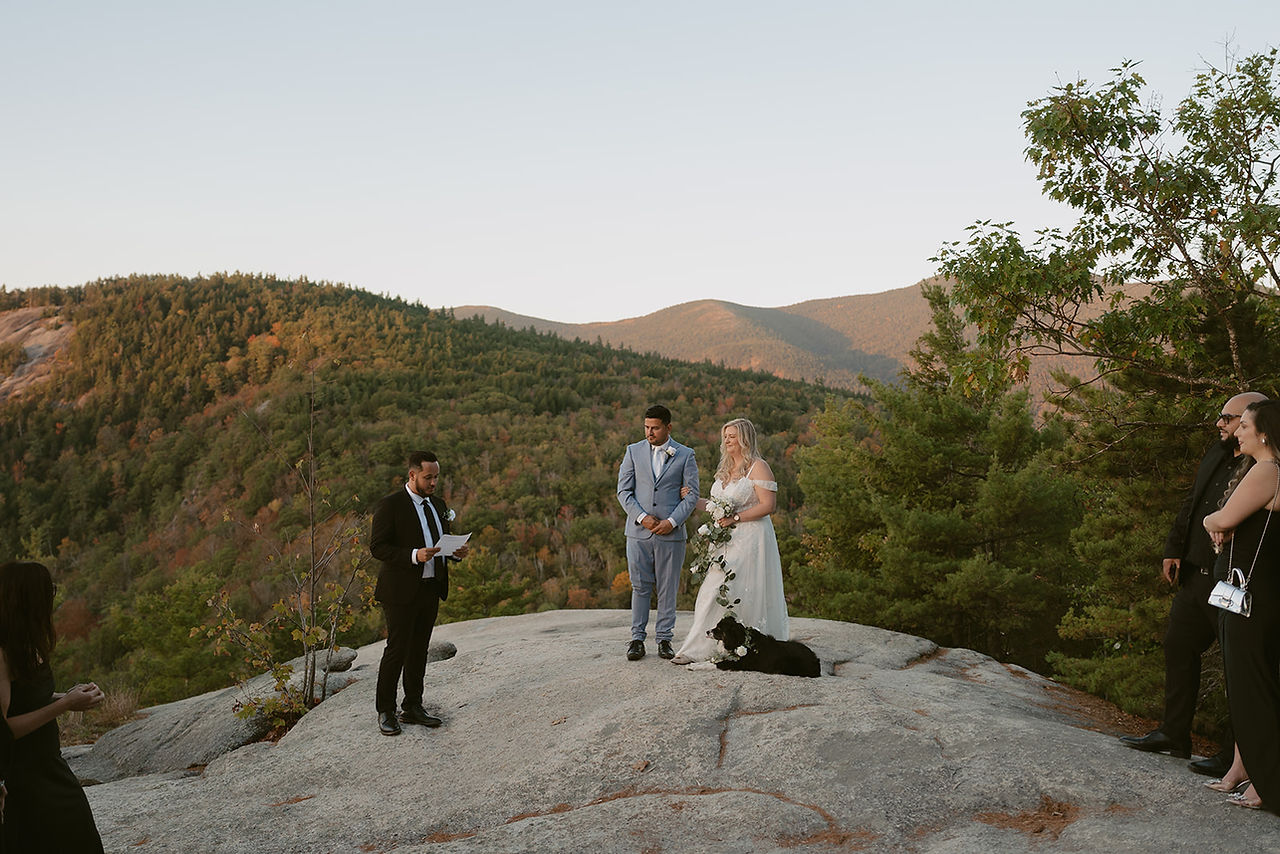 Couple during ceremony on cathedral ledge with their dog by their feet