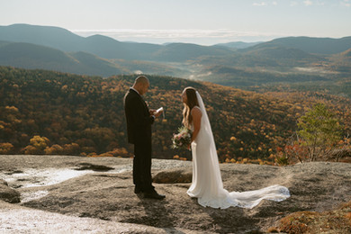 Couple on mountain top in franconia notch on elopement day enjoying sunrise.