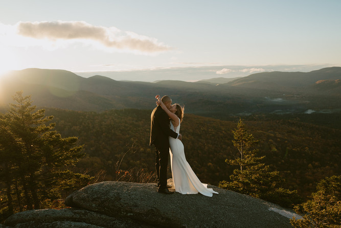 Couple on mountain top in franconia notch on elopement day enjoying sunrise.