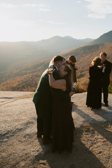 White Mountains Micro Wedding with family on a mountain top at sunrise in the fall mom hugging groom