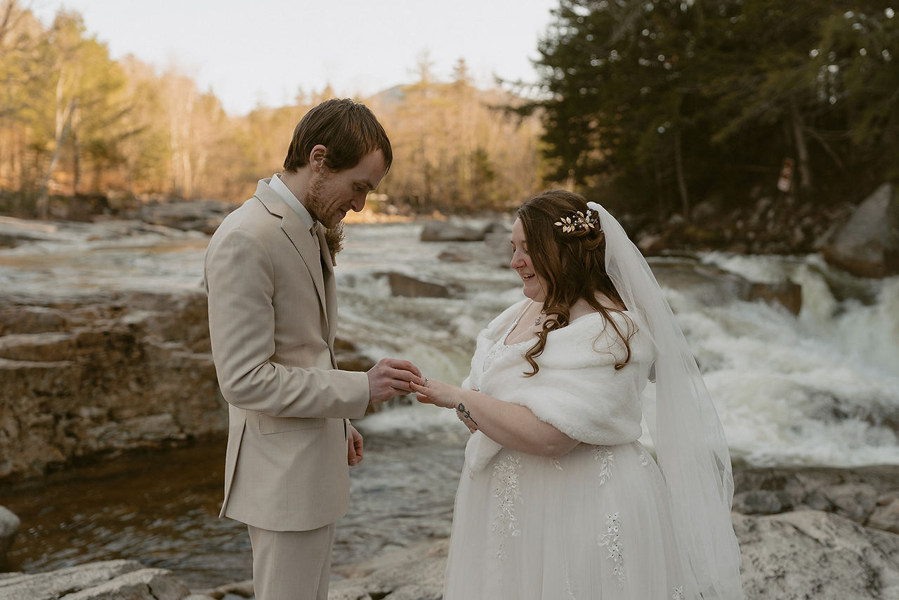 Couple sharing vows with waterfall behind them for loon mountain elopement