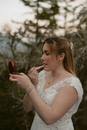 bride putting on lip stick on mountain top elopement day in the white mountains in pinkham notch