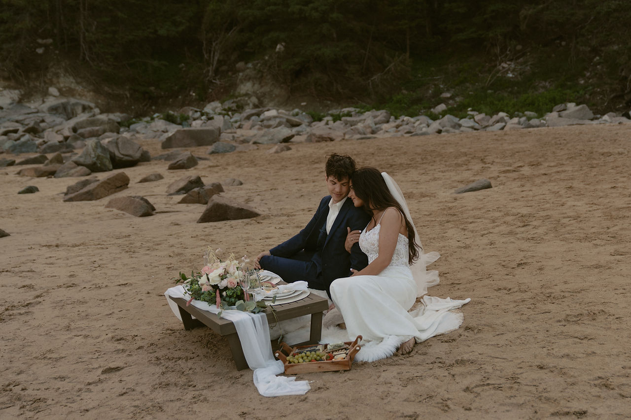 couple enjoying luxury picnic on sand beach after sand beach wedding in acadia