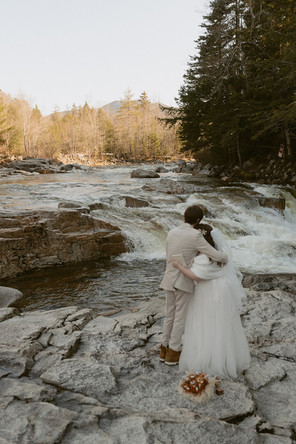 Couple sharing vows with waterfall behind them for loon mountain elopement