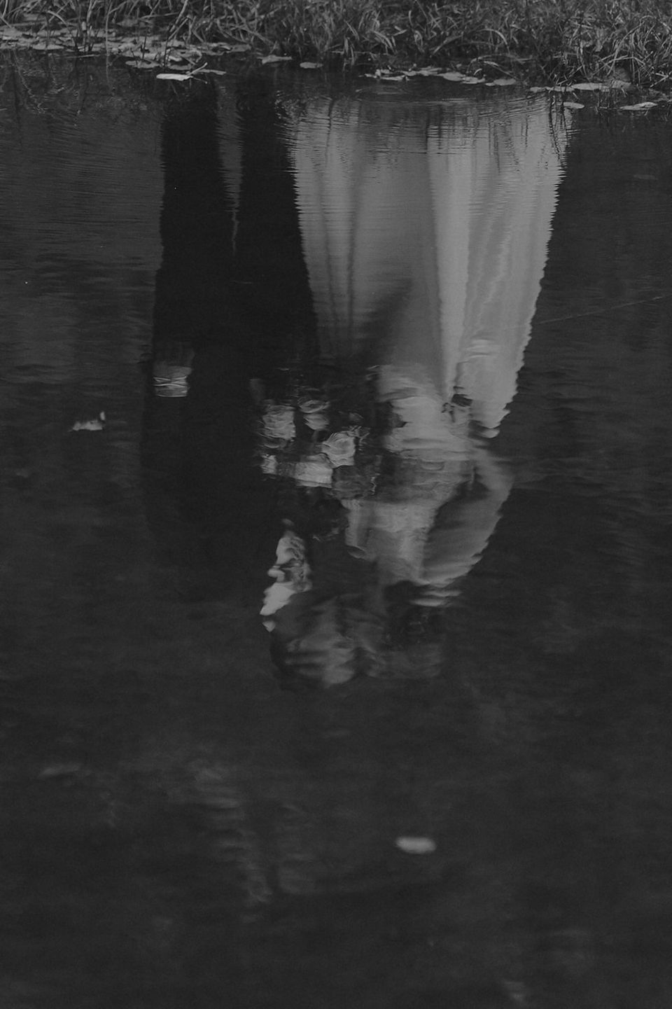 Couple exploring lake side in moody weather on a fall day in the white mountains after micro wedding