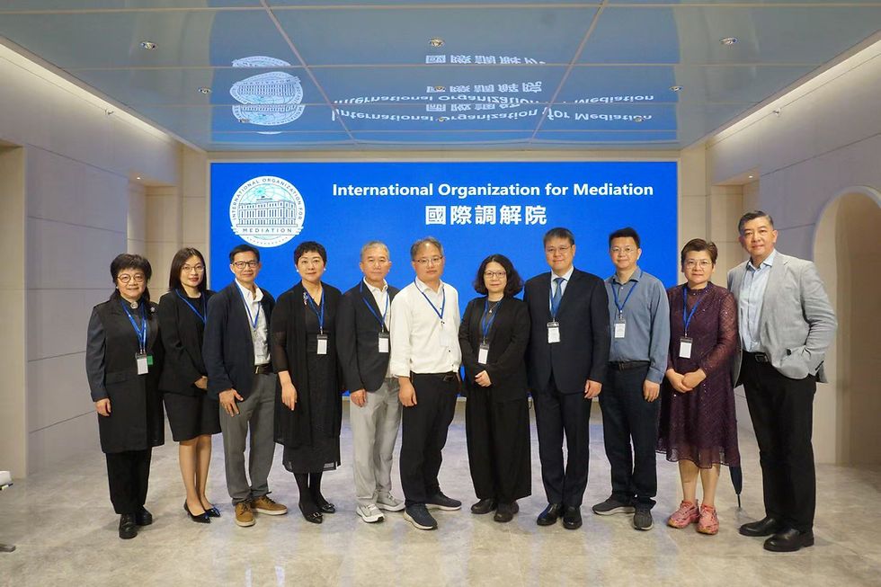 Group photo of the MCMC delegation standing in front of a blue screen at the International Organization for Mediation. MCMC Hong Kong visit.