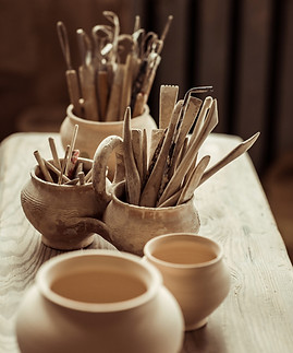 Close up of paint brushes with pottery tools in bowls on table.jpg