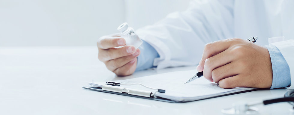 doctor with a medicine bottle in one hand, and a pen in the other hand, writing on a paper