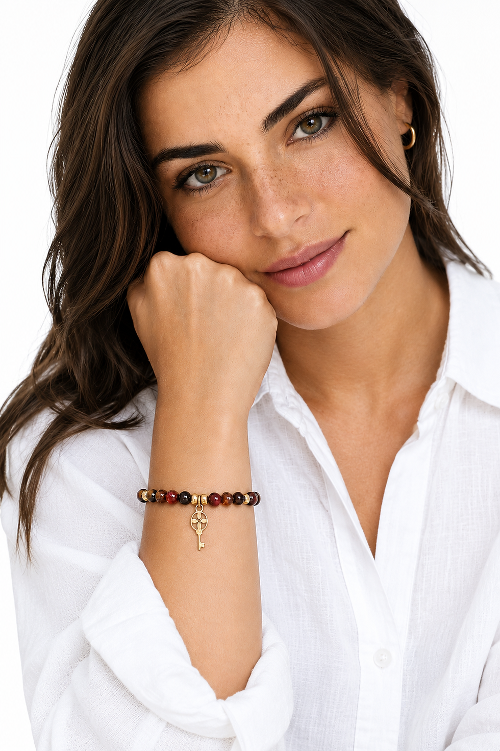 Detalle en la muñeca de la pulsera artesanal Kanerian con piedras de ágata carneliana marrón y amuleto de llave.