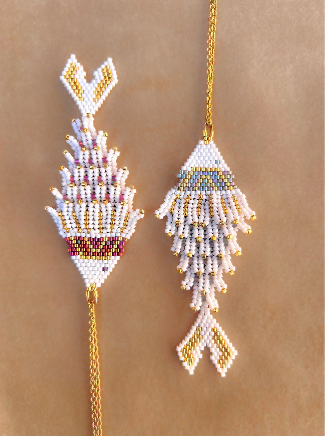 Colgante Pez tejido a mano con cuentas Delica de Miyuki en tonos dorado, blanco, azul y burdeos, formando un diseño detallado con forma de pez. La cadena es de acero hipoalergénico, ideal para un uso cómodo y duradero. Una joya artesanal única y llamativa, perfecta para quienes buscan un accesorio con inspiración marina y estilo sofisticado.
