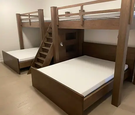 A pair of handcrafted beds featuring custom bed frames made of rich, dark wood. These custom wood beds are designed as a built-in bunk system with a staircase, showcasing high-end custom bedroom furniture and bespoke beds perfect for a modern home in GTA.