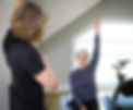 Personal trainer showing older woman how to do exercise for shoulder joint mobility