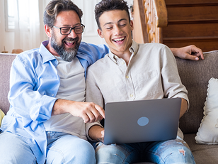 Parent and student smiling while reviewing college acceptance results together on a laptop.
