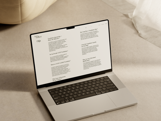 Un MacBook mostrando el sitio web de una traductora profesional está colocado en un suelo de color claro en una habitación con iluminación suave. La pantalla presenta a Inés Bellesi como traductora e intérprete certificada por NAATI de inglés a español. Un otomano beige con textura y cortinas blancas fluidas aportan una estética minimalista y elegante al ambiente.