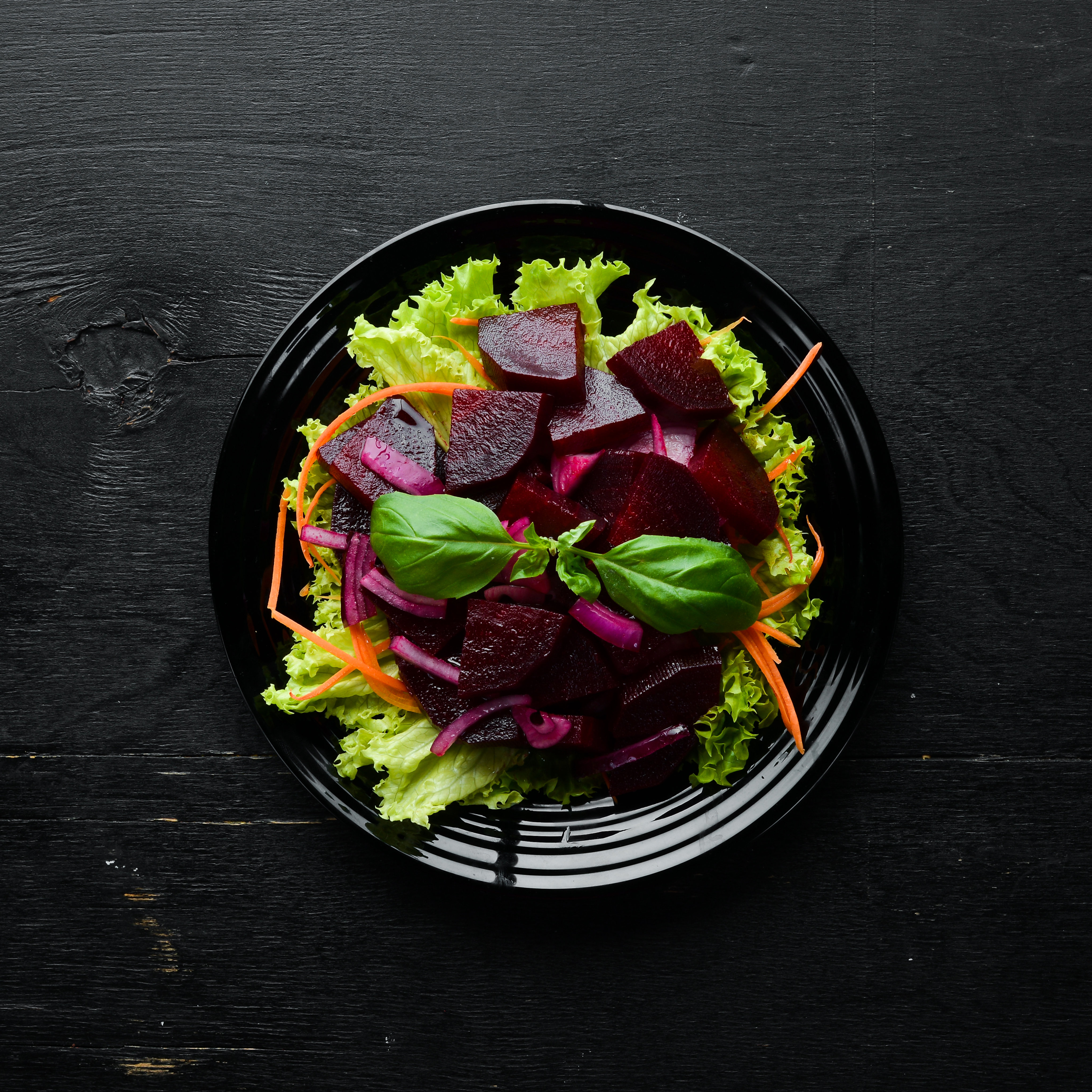 Rote-Bete-Salat mit Basilikum auf schwarzem Teller
