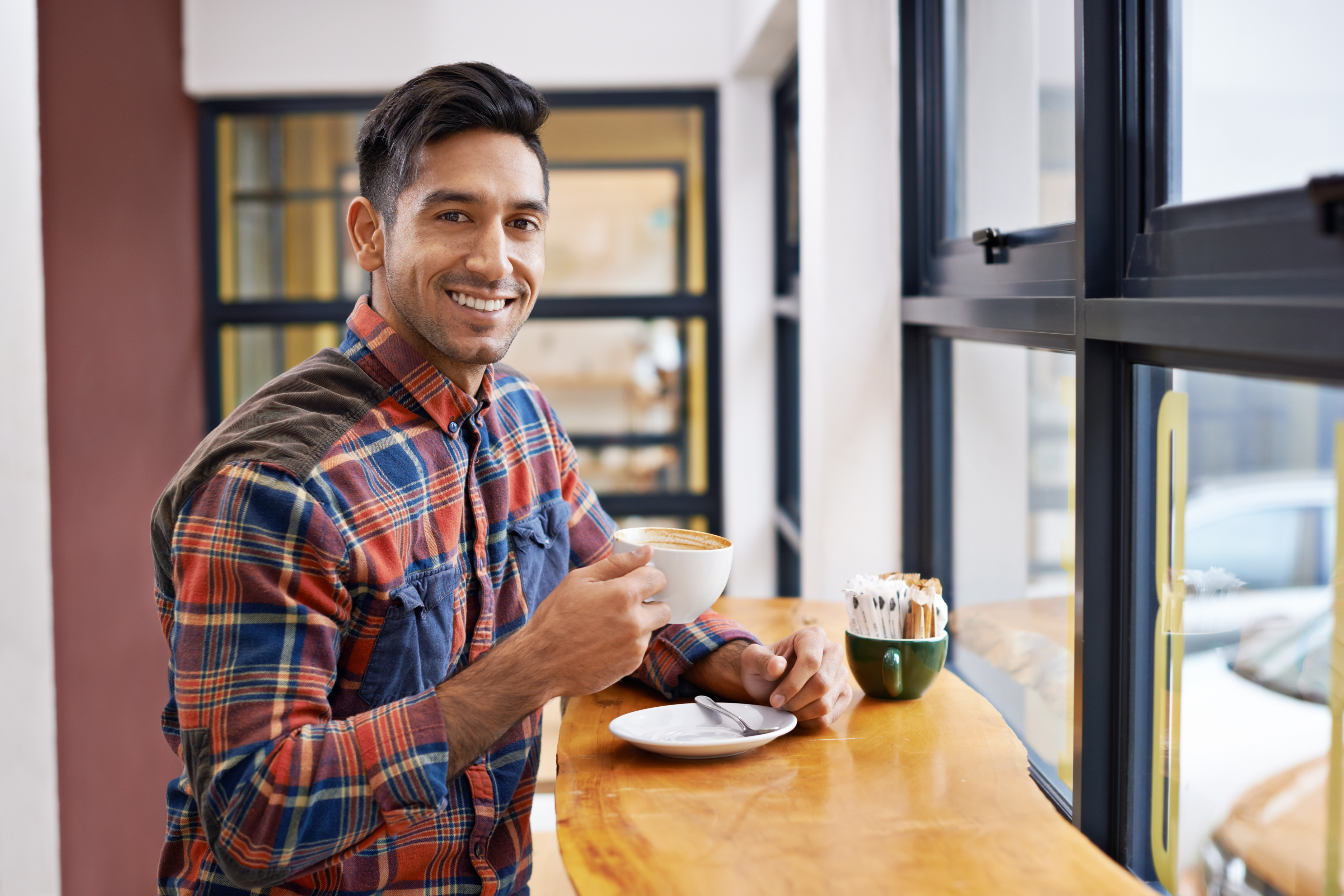 happy-man-portrait-relax-with-coffee-by-window-morning-breakfast-start-day-male-person-wit