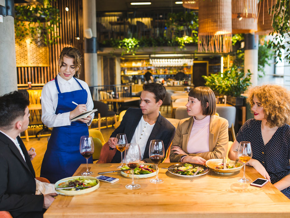 Kellnerin notiert Bestellung von Gästen in gehobenem Restaurant. Essen und Getränke.