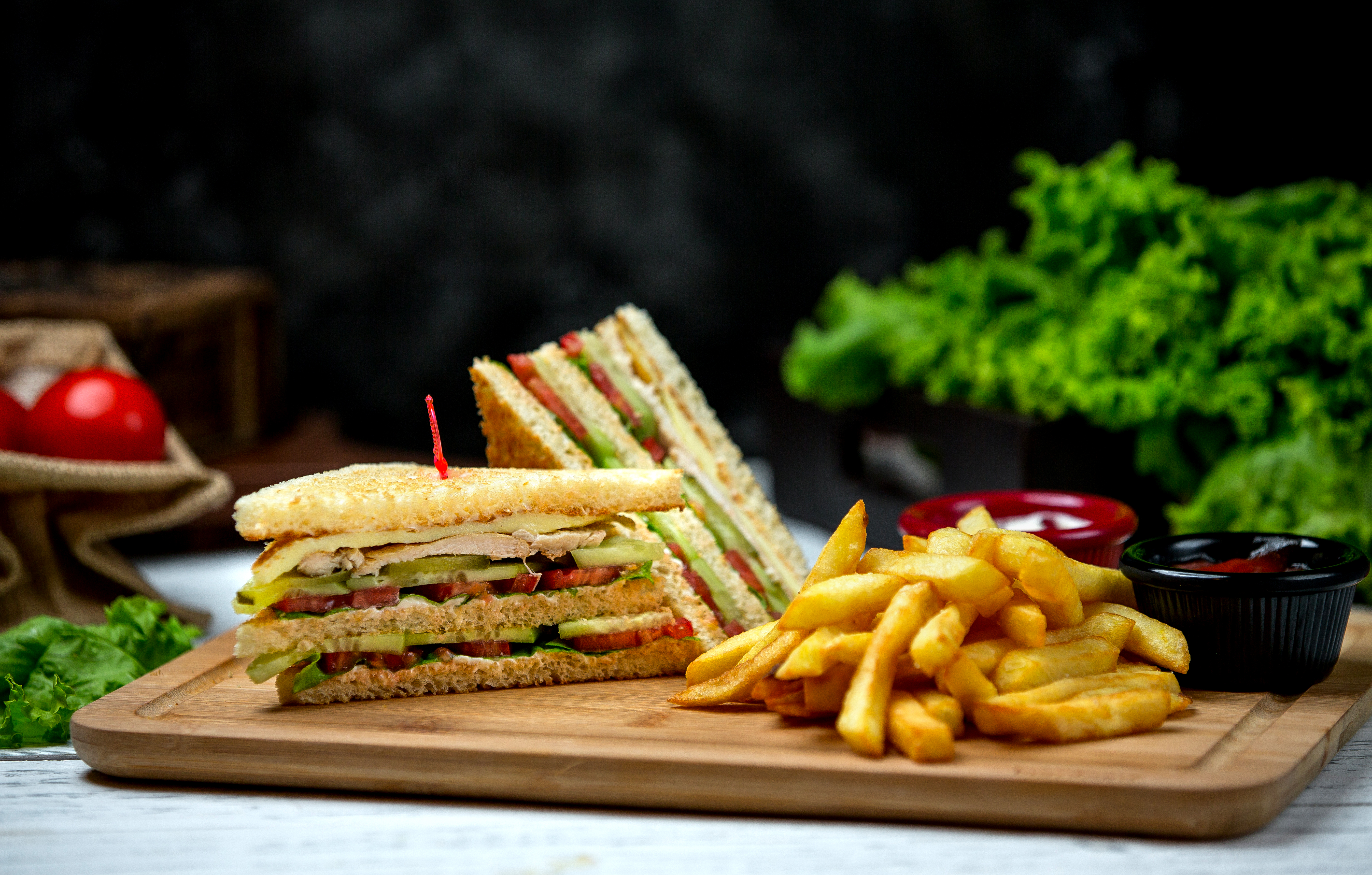 Ein Club-Sandwich, Pommes Frites, Tomaten und Salat auf einem Holzbrett. Mein Site 14