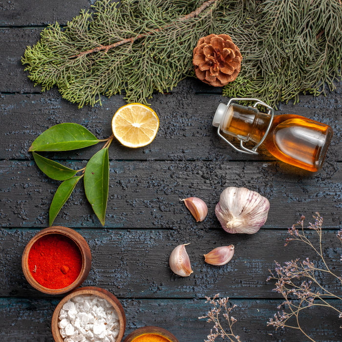 Various ingredients on a wooden table, including spices, lemon, and garlic.