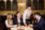 Waiter serving fruit platter to happy couple