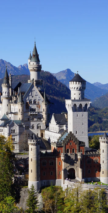 Schloss Neuschwanstein in Bayern mit Bergen und See im Hintergrund.