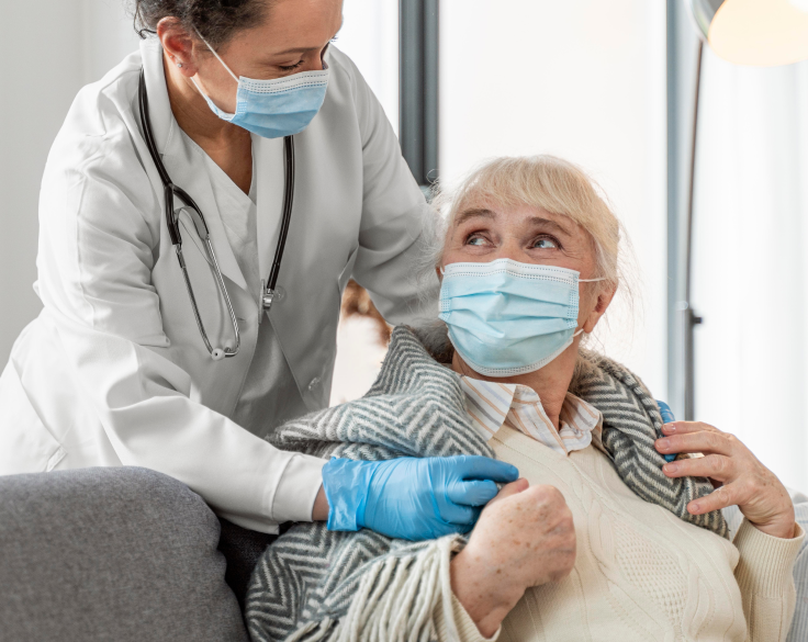 Healthcare worker assists elderly woman, both wearing masks