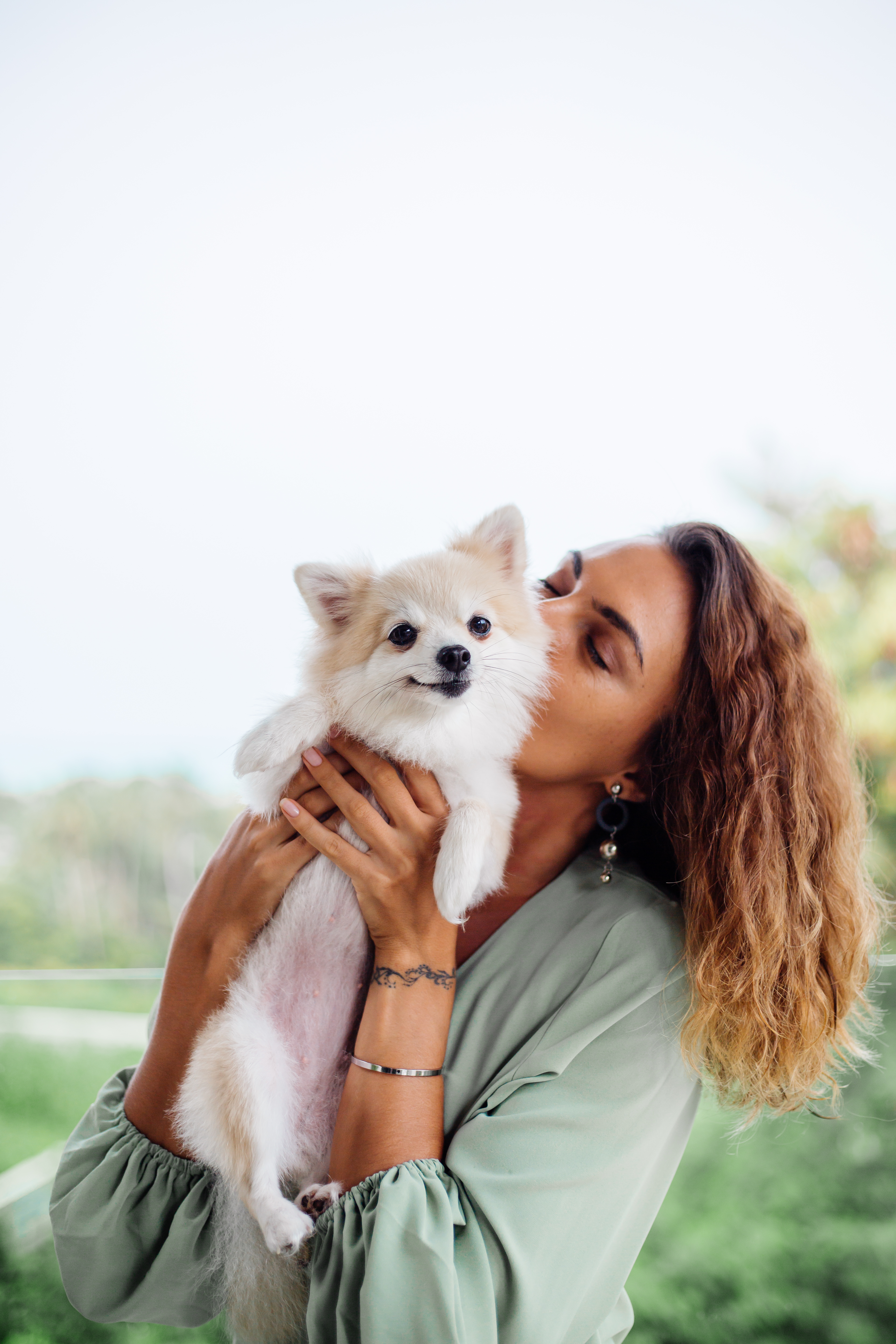 outdoor-portrait-curly-european-tanned-woman-holds-happy-pet-dog-pomeranian-spitz