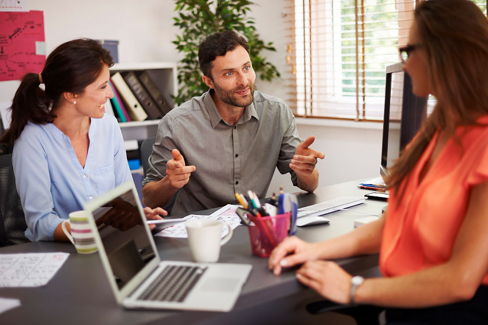 Team discussing project at office desk with laptop and documents