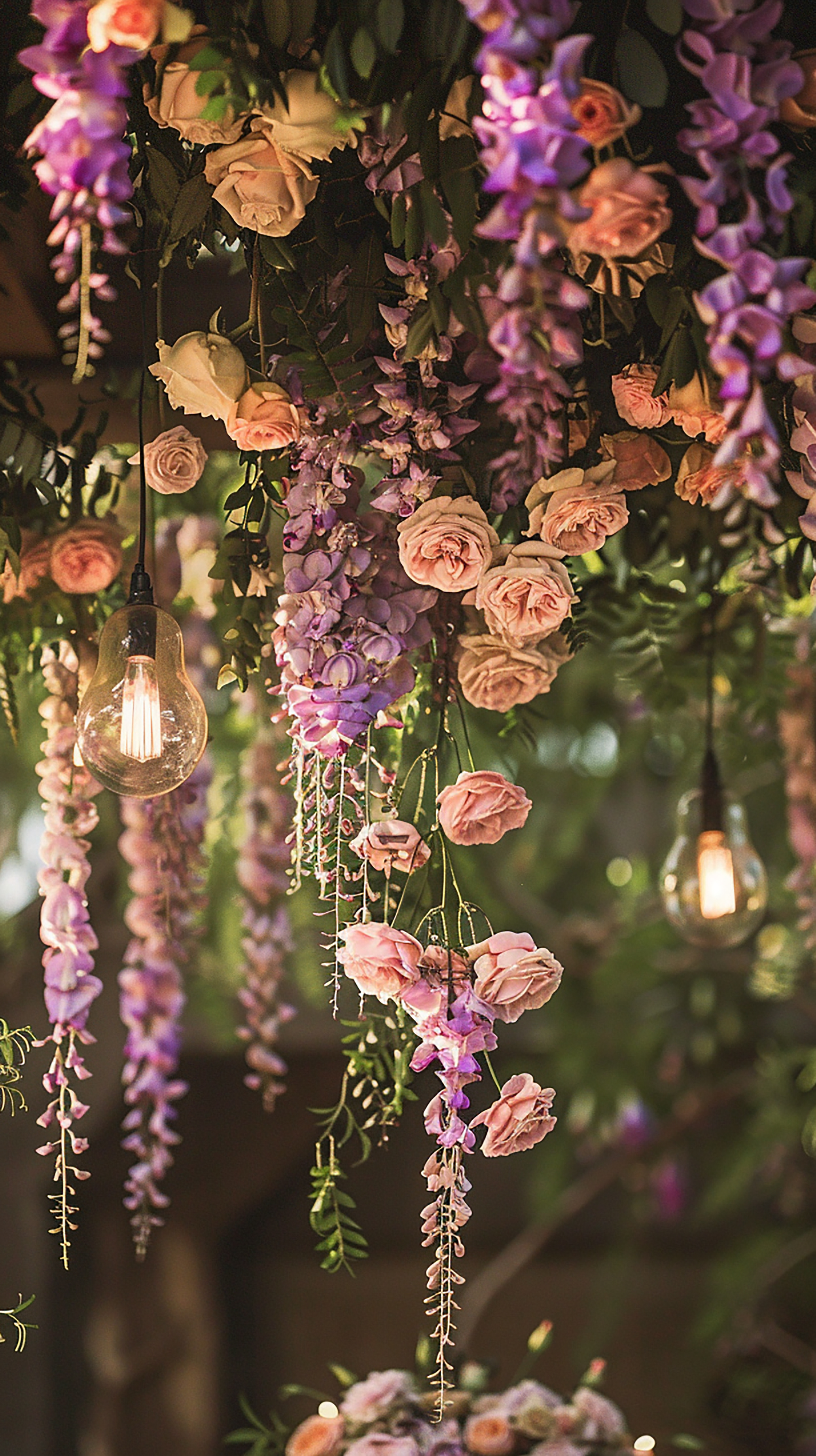 Hängende Blumenarrangements mit Rosen und Lichterketten für eine romantische Dekoration.