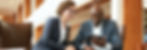 white woman and black man using tablet and discussing business in hotel lobby