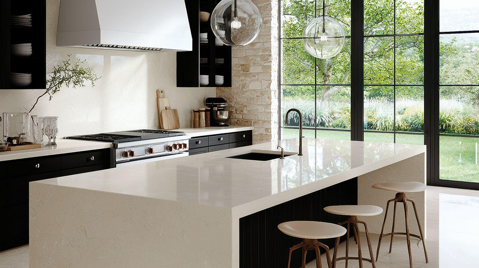 Modern kitchen with a white island, black cabinets, three stools, and large windows overlooking a green garden.