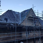 A stone house under renovation with scaffolding surrounding it