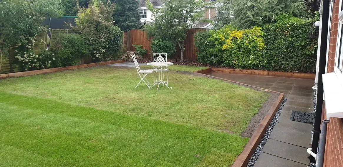 A well-kept garden features a green lawn with a white metal table