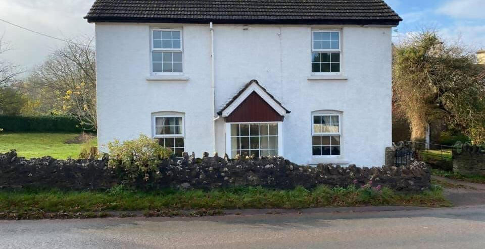 White two-story cottage house featuring a low stone wall