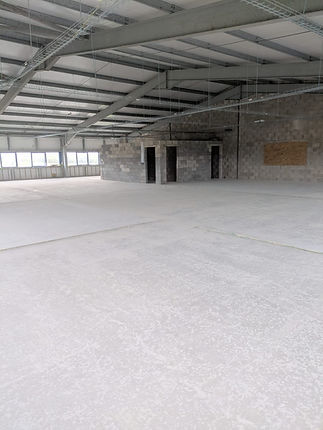 Spacious commercial building interior with exposed steel roof structure and level floor