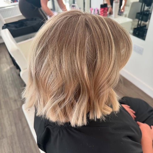 Blonde bob haircut with soft waves viewed from behind in a salon
