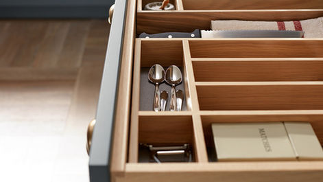Top-down detail shot of an open solid wood cutlery drawer.