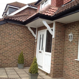Main entrance of a brick home showing a white uPVC front door sheltered by a small pitched tiled porch canopy