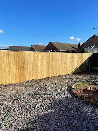 A newly fitted wooden garden fence panel with decorative gravel borders