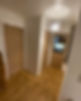 Narrow hallway with light wood flooring, white walls, two wooden doors