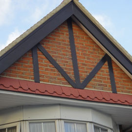 House gable end featuring decorative mock Tudor timber boards above an elegant bay window roof structure