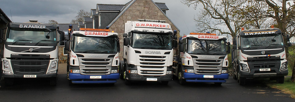 Fleet of white D.W. Parker Tipper and haulage lorries lined up outdoors in Ardrossan yard