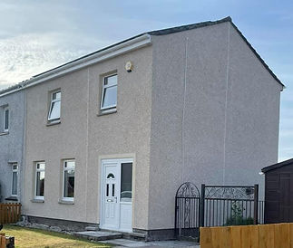 A beige, two-story house with four windows and a white door
