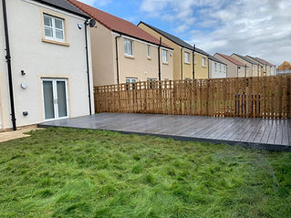 Newly built grey timber decking terrace in the back garden of a modern semi detached house